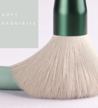 Makeup brush with green handle and beige bristles on a light background, with text 'SOFT EXQUISITE'.