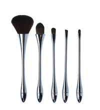 Set of five makeup brushes with metallic handles on a white background