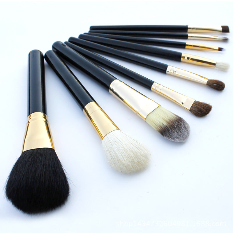 Set of makeup brushes with black and gold handles on a white background