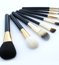 Set of makeup brushes with black and gold handles on a white background