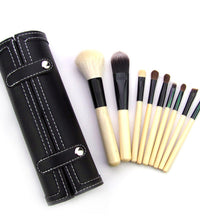 Set of makeup brushes with a black leather holder on a white background