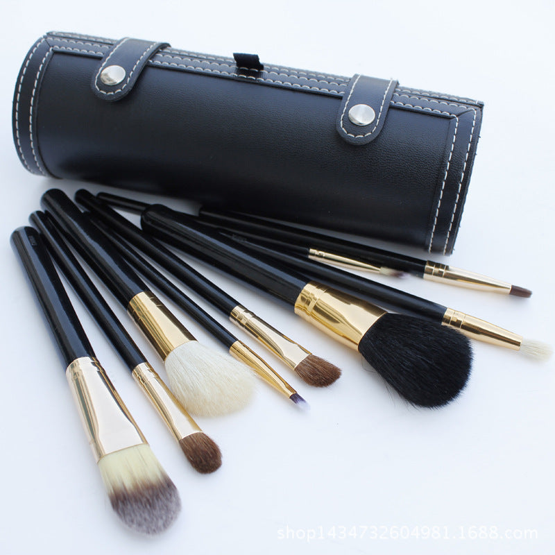 Set of makeup brushes with black and gold handles in a black leather case on a white background