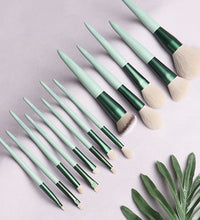 Set of makeup brushes with green and beige handles on a light gray background